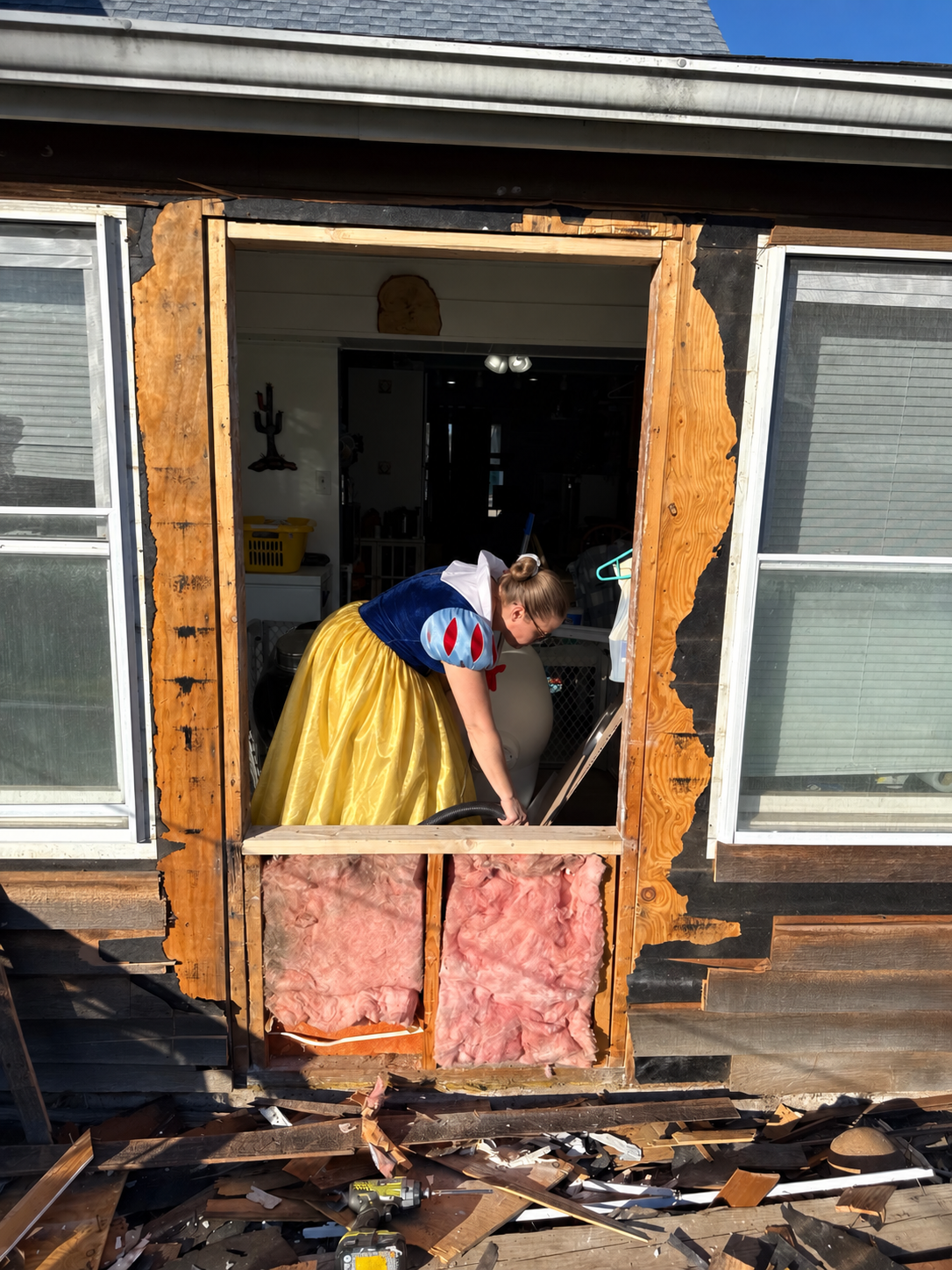 Snow White working inside a partially demolished exterior wall during a home renovation
